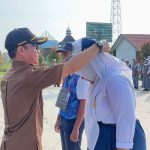 Kepala Sekolah Syahrul, S.Pd., Saat Memasang Kartu Pengenal Murid. (Foto : Dok. Pribadi)